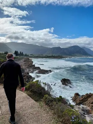 a man walking down a path looking at the ocean at Nerf-af Cottage at Onrus, Hermanus in Hermanus