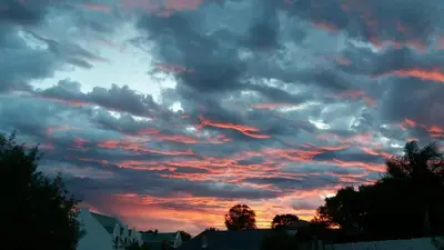 a cloudy sky at sunset with houses and trees at Nerf-af Cottage at Onrus, Hermanus in Hermanus