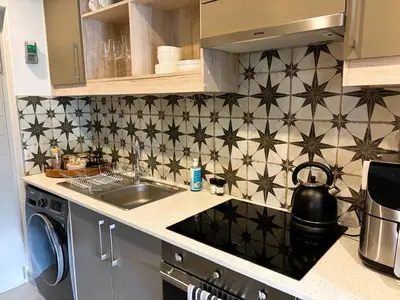 a kitchen with black and white tiled wall at Bachelors Unit at The Den in Stellenbosch