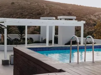 a swimming pool with a pavilion next to a house at Bachelors Unit at The Den in Stellenbosch