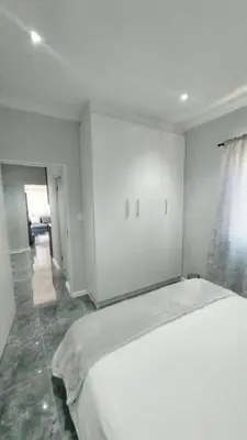 a white bedroom with a large bed and a hallway at B3 bnb House
