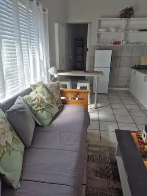 a living room with a couch and a kitchen at Suné's Self Catering 1 in Worcester