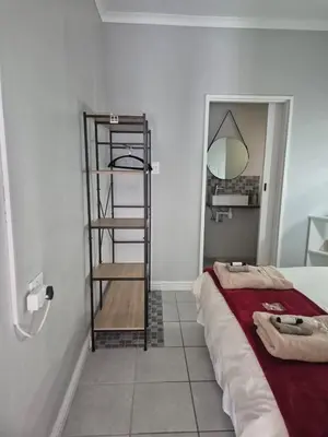 a room with a bed and a shelf next to a mirror at Suné's Self Catering 1 in Worcester