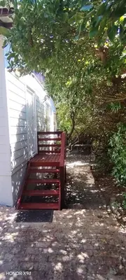 a red bench sitting on the side of a house at Pet Friendly Sandbaai in Hermanus