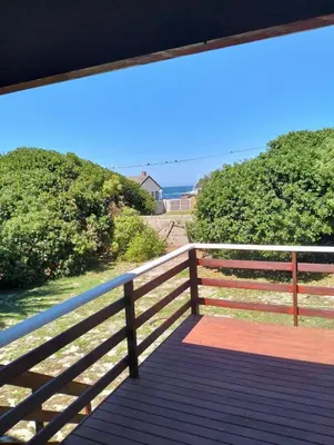 a wooden bench on a fence with a view of the ocean at Pet Friendly Sandbaai in Hermanus