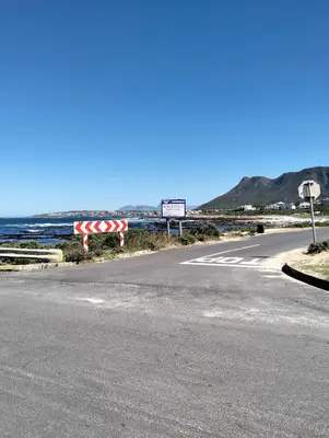 an empty road with a stop sign next to the ocean at Pet Friendly Sandbaai in Hermanus