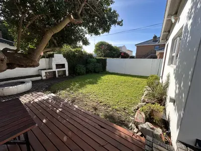 a backyard with a wooden deck and a yard at Protea Escape - Apartment in Hermanus