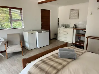 a bedroom with a refrigerator and a table and a chair at Protea Escape - Apartment in Hermanus