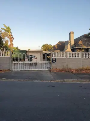 a white fence in front of a house at Ludinz Self Catering Guest House