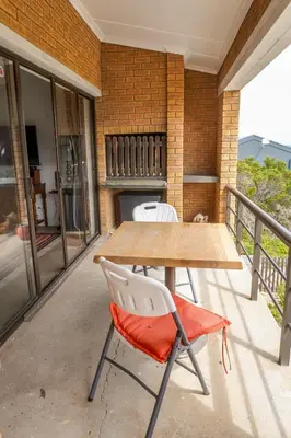 a wooden table and two chairs on a balcony at Leah's View in Pringle Bay