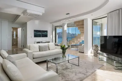 a living room with white furniture and a large tv at Main Hibernian Penthouse in Strand