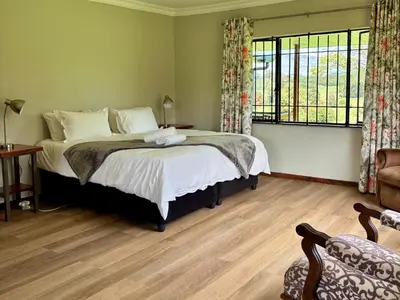 a bedroom with a bed and a large window at Shiloh Lodges Kamberg in Sir Lowry Pass