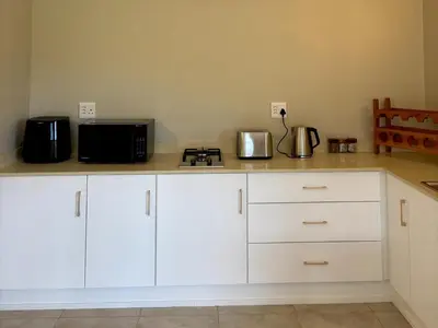a kitchen with white cabinets and a black microwave at Shiloh Lodges Kamberg in Sir Lowry Pass