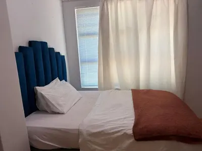a bed with a blue headboard and a window at Home of peace self catering accommodation