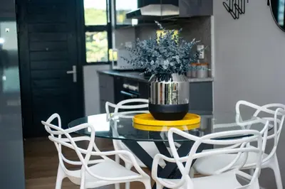 a dining room table with chairs and a vase with flowers at Sea Facing 2 Bedroom Apartment In Burmeister On Park, Milnerton in Cape Town