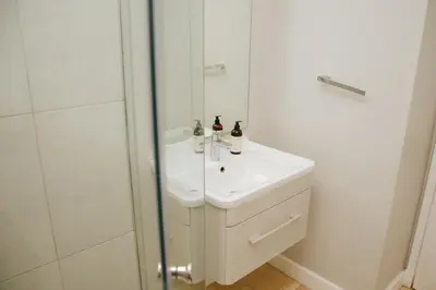 a white bathroom with a sink and a shower at Sea Facing 2 Bedroom Apartment In Burmeister On Park, Milnerton in Cape Town