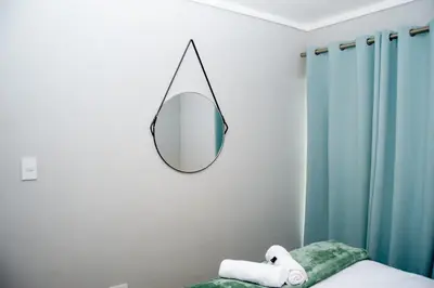 a mirror hanging on a wall next to a bed at Sea Facing 2 Bedroom Apartment In Burmeister On Park, Milnerton in Cape Town