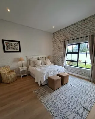 a bedroom with a bed and a brick wall at Bird's Landing in Hermanus