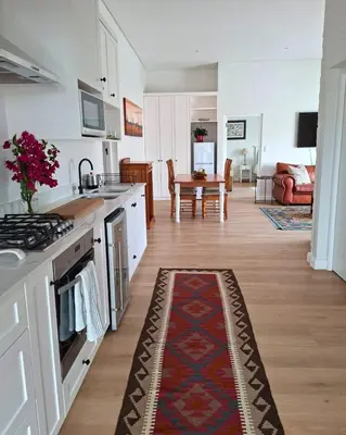 a kitchen and living room with a rug on the floor at Bird's Landing in Hermanus