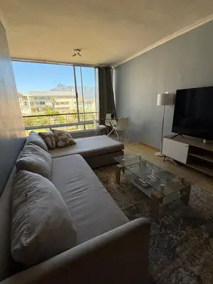 a living room with a couch and a flat screen tv at Cozy Apartment with Table Mountain and beach views in Cape Town