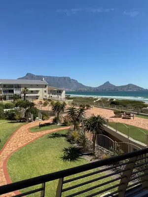 a view of the beach from the balcony of a resort at Cozy Apartment with Table Mountain and beach views in Cape Town