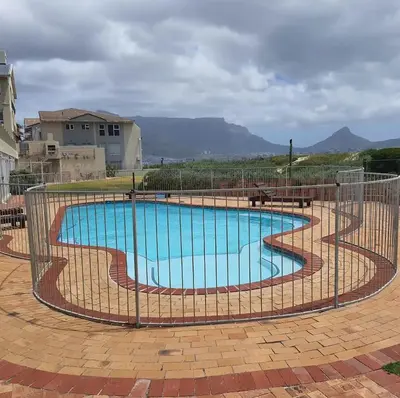 a swimming pool with a fence around it at Cozy Apartment with Table Mountain and beach views in Cape Town