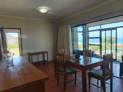 a dining room with a table and chairs and a large window at Starfish - The rockpool house in Bettyʼs Bay