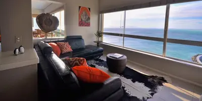 a living room with a couch and a large window at Celtic Manor Boutique Guest House in Gordonʼs Bay