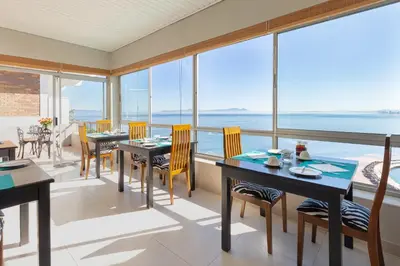 a dining room with a view of the ocean at Celtic Manor Boutique Guest House in Gordonʼs Bay