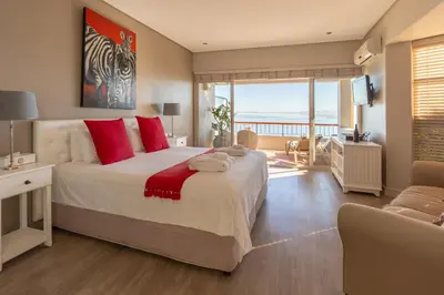 a bedroom with a large bed with red pillows at Celtic Manor Boutique Guest House in Gordonʼs Bay