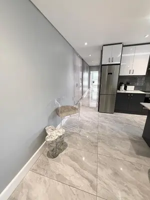 a kitchen with white walls and a table and a chair at Canal Walk Luxury 2 Bedroom Apartments in Cape Town