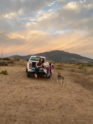 two people sitting in the back of a truck with a dog at The Old Silver Oaks Farm Cottage