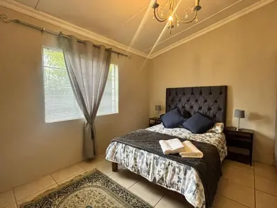 a bedroom with a bed with blue pillows and a chandelier at The Old Silver Oaks Farm Cottage