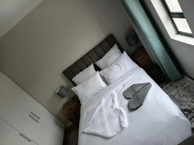 a bedroom with a bed with white sheets and pillows at Coastal Guest House with Free Parking and Braai Area in Cape Town