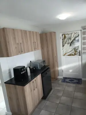 a kitchen with wooden cabinets and a counter top at Coastal Guest House with Free Parking and Braai Area in Cape Town