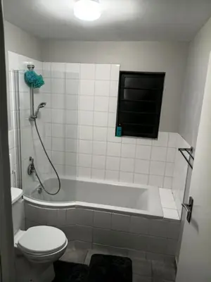 a bathroom with a tub and a toilet and a window at Coastal Guest House with Free Parking and Braai Area in Cape Town