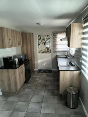 a kitchen with wooden cabinets and a white door at Coastal Guest House with Free Parking and Braai Area in Cape Town