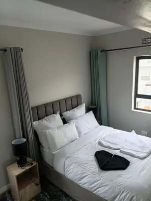 a bedroom with a large bed with white sheets and pillows at Coastal Guest House with Free Parking and Braai Area in Cape Town