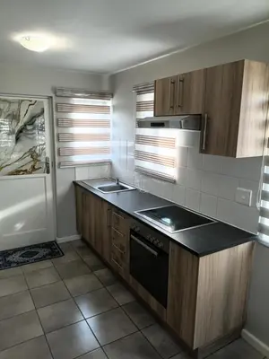 a kitchen with wooden cabinets and a black counter top at Coastal Guest House with Free Parking and Braai Area in Cape Town