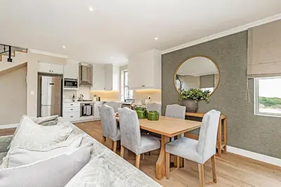 a kitchen and living room with a table and chairs at L'Ermitage Chateau and Villas at Villa 80 in Franschhoek