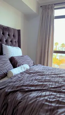a bed in a bedroom with a large window at De Groove Luxury Homes in Cape Town