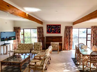 a living room with a couch and a table and chairs at Pura Vida Hermanus in Hermanus