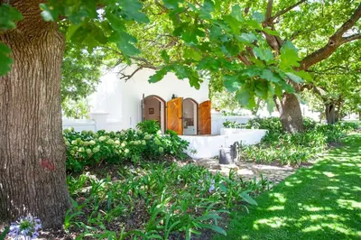 a garden with trees and a white house at The Oak Cottage in Wellington