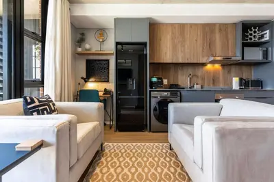 a living room with two white couches and a kitchen at Stylish Executive Studio with Balcony in Riverlands, Observatory in Cape Town