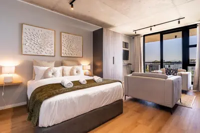 a large bedroom with a large bed and a chair at Stylish Executive Studio with Balcony in Riverlands, Observatory in Cape Town