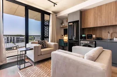 a living room with two couches and a kitchen at Stylish Executive Studio with Balcony in Riverlands, Observatory in Cape Town