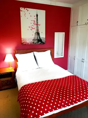 a bedroom with a bed with a red wall at Cape Dutch Family Home in the Winelands in Somerset West
