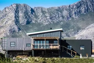 a house on a hill with mountains in the background at The Red Door in Pringle Bay