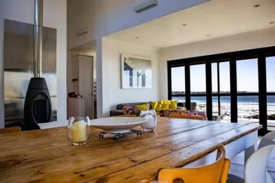 a large wooden table in a living room with a view of the ocean at The Red Door in Pringle Bay