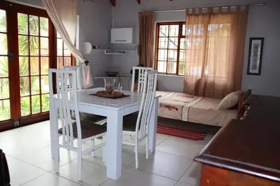 a white table and chairs in a room with a bed at 7th Heaven Lodge in Gordonʼs Bay